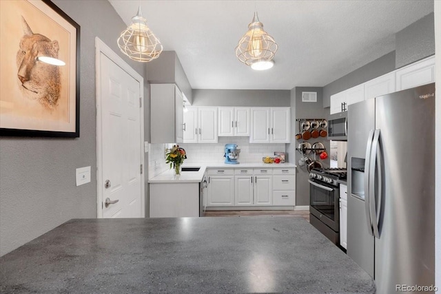 1568 S Osceola Way, Denver, CO 80219 - kitchen with appliances with stainless steel finishes, white cabinetry, tasteful backsplash, a textured wall, and pendant lighting