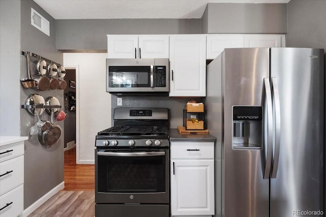1568 S Osceola Way, Denver, CO 80219 - kitchen featuring stainless steel appliances, light wood-style floors, white cabinets, baseboards, and dark countertops