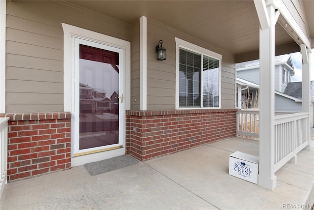 property entrance featuring covered porch and brick siding