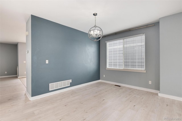 unfurnished room with baseboards, visible vents, a chandelier, and wood finished floors