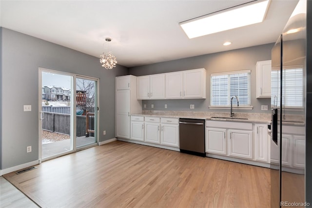 kitchen with light wood finished floors, a wealth of natural light, appliances with stainless steel finishes, white cabinets, and a sink