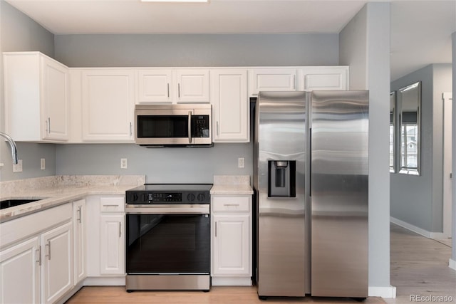 kitchen featuring white cabinetry, stainless steel appliances, a sink, and light countertops