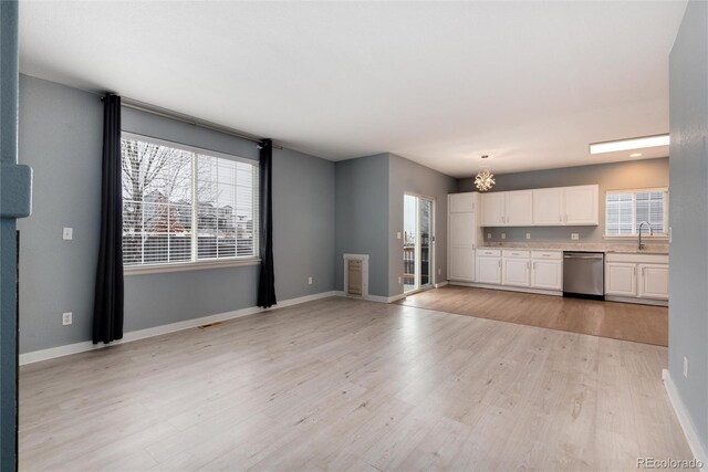 unfurnished living room featuring light wood-type flooring, a sink, and baseboards