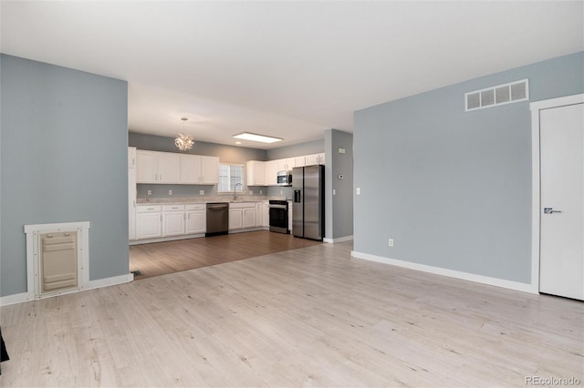 kitchen featuring stainless steel appliances, a sink, visible vents, light countertops, and light wood-type flooring