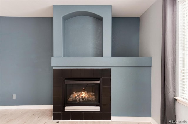 interior details featuring a tile fireplace, baseboards, and wood finished floors