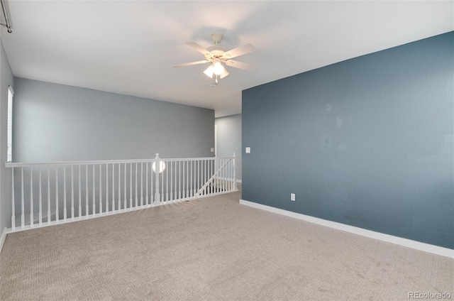 carpeted spare room featuring ceiling fan and baseboards