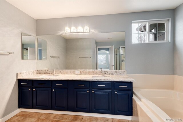 bathroom featuring a sink, baseboards, a shower stall, a bath, and double vanity