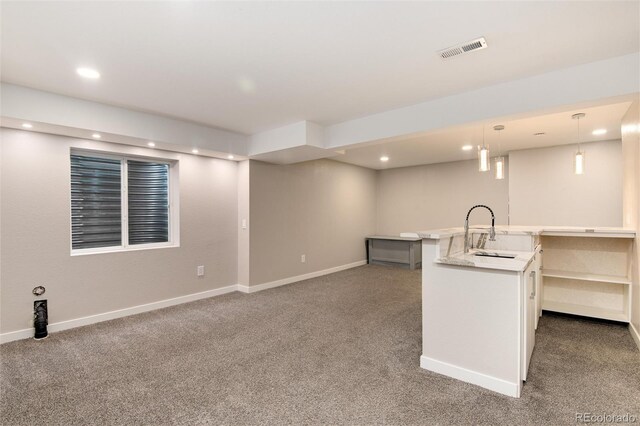 finished basement with carpet floors, a sink, visible vents, and baseboards