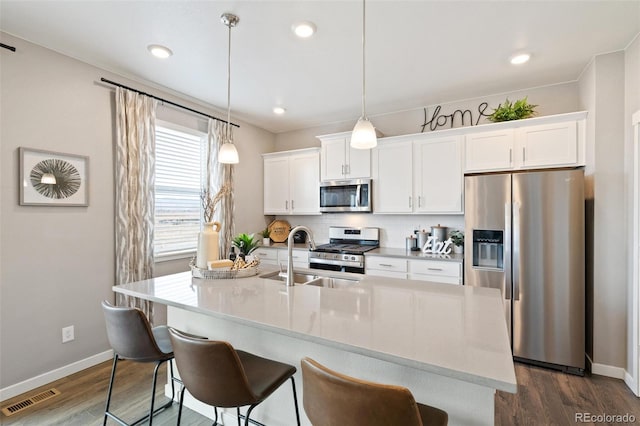 kitchen featuring a kitchen island with sink, stainless steel appliances, sink, and pendant lighting