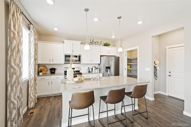 kitchen featuring white cabinetry, a kitchen island with sink, stainless steel appliances, and pendant lighting