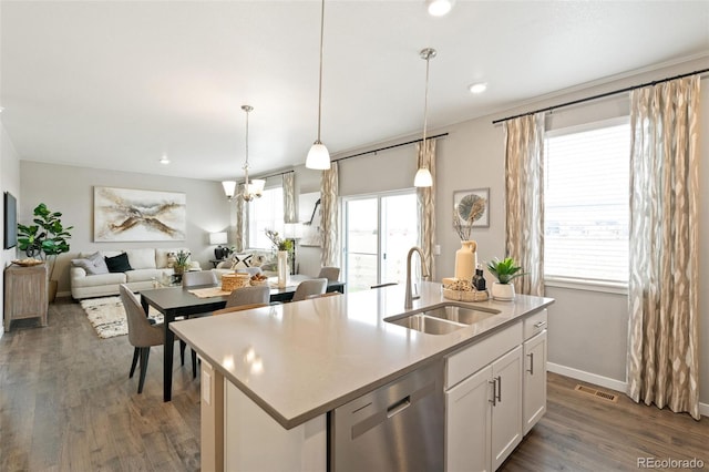 kitchen featuring white cabinets, hanging light fixtures, a kitchen island with sink, stainless steel dishwasher, and sink