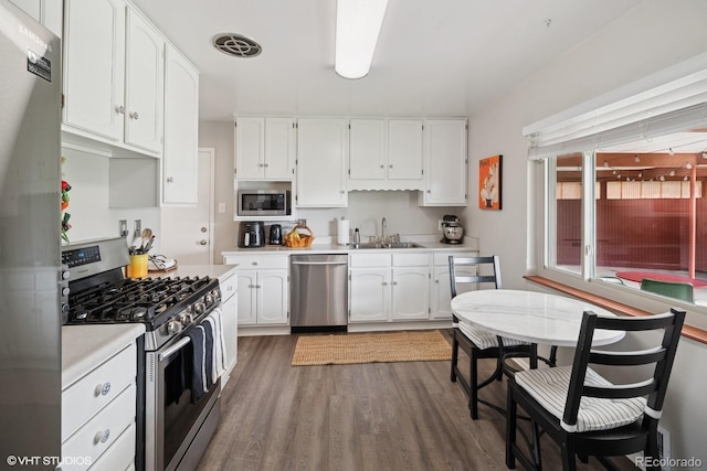 2792 S Stuart St, Denver, CO 80236 - kitchen featuring appliances with stainless steel finishes, a sink, white cabinetry, and wood finished floors