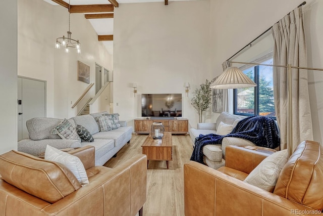 living room with a notable chandelier, beam ceiling, light hardwood / wood-style floors, and a high ceiling