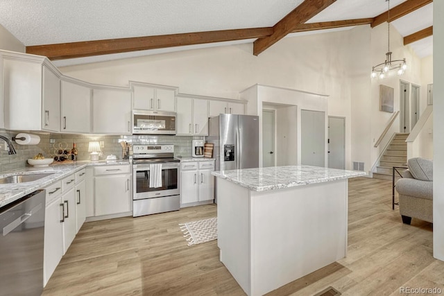 kitchen featuring white cabinetry, sink, hanging light fixtures, a center island, and stainless steel appliances