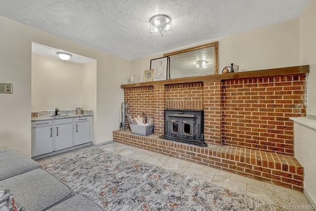 living room featuring sink, a textured ceiling, and a wood stove