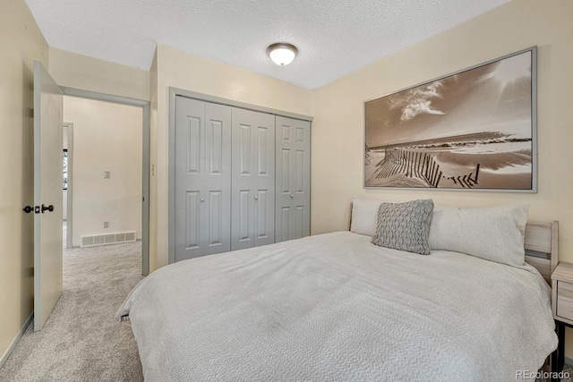 carpeted bedroom with a closet and a textured ceiling