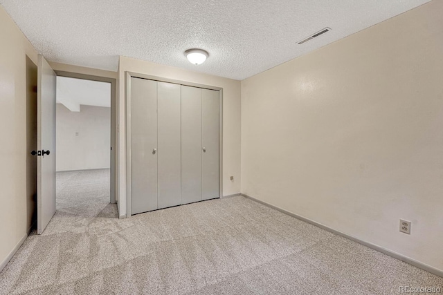 unfurnished bedroom featuring light carpet, a closet, and a textured ceiling