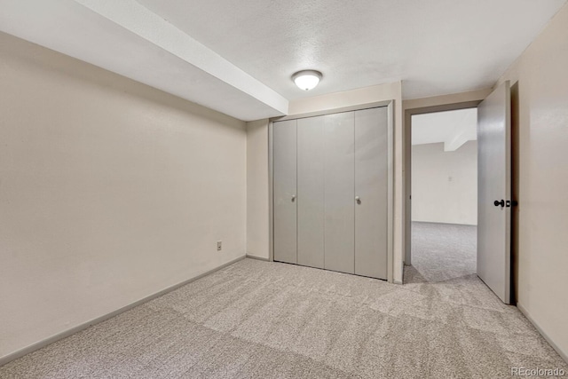 unfurnished bedroom featuring light carpet, a textured ceiling, and a closet