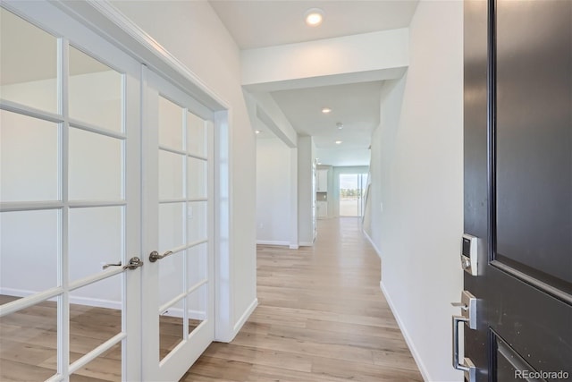 corridor featuring light wood-type flooring, baseboards, french doors, and recessed lighting