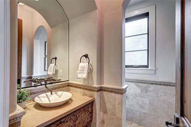 bathroom featuring tile walls, wainscoting, and vanity