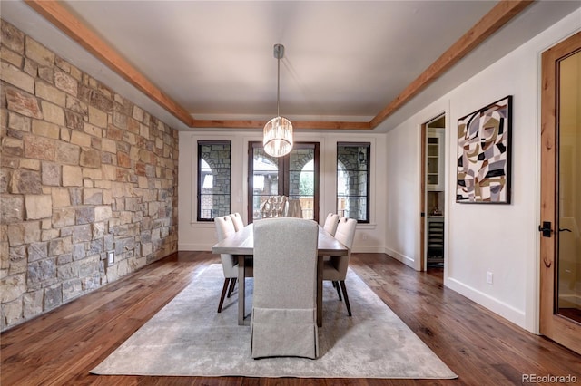 dining space with baseboards, a chandelier, a raised ceiling, and dark wood-style flooring