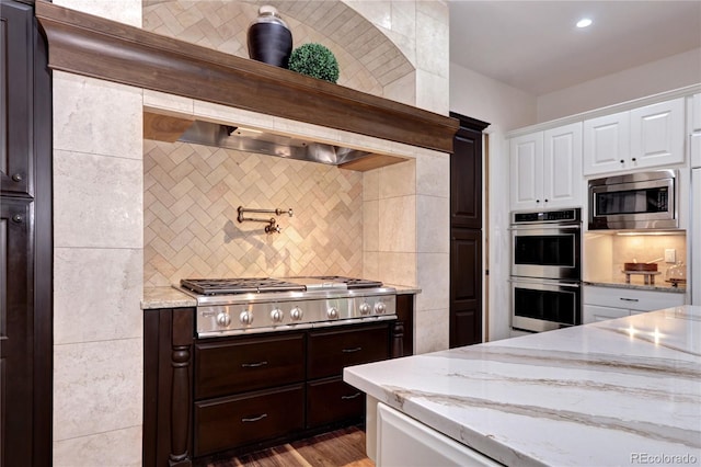 kitchen with white cabinets, decorative backsplash, appliances with stainless steel finishes, and light stone counters