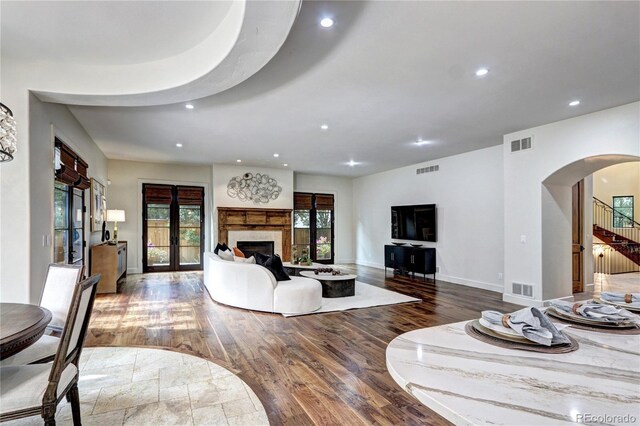 living area with arched walkways, wood finished floors, visible vents, and recessed lighting