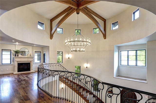 staircase with a high ceiling, a healthy amount of sunlight, and wood finished floors