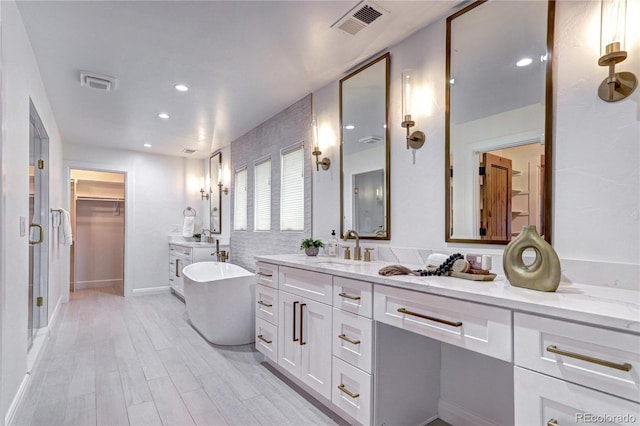 full bathroom featuring a freestanding bath, wood finished floors, visible vents, and recessed lighting