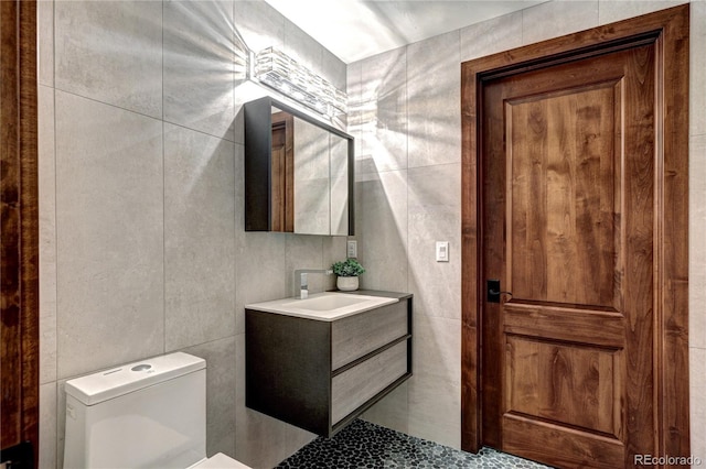 bathroom featuring tile patterned flooring, tile walls, toilet, and vanity