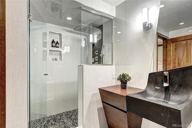 bathroom featuring recessed lighting, a shower stall, and tile walls