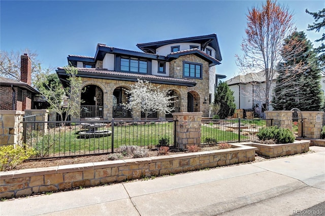 view of front of house featuring a fenced front yard, stone siding, a front yard, and covered porch
