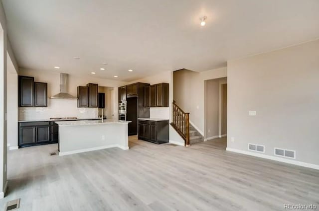 kitchen with light wood-style floors, visible vents, and wall chimney range hood