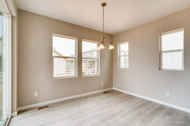 unfurnished room with a chandelier, visible vents, light wood-style flooring, and baseboards