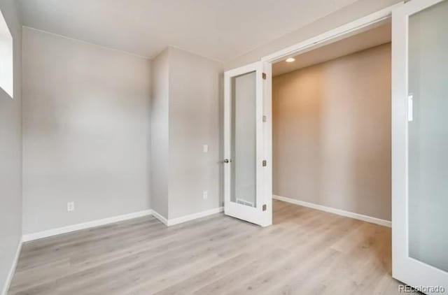 spare room featuring light wood-type flooring and baseboards