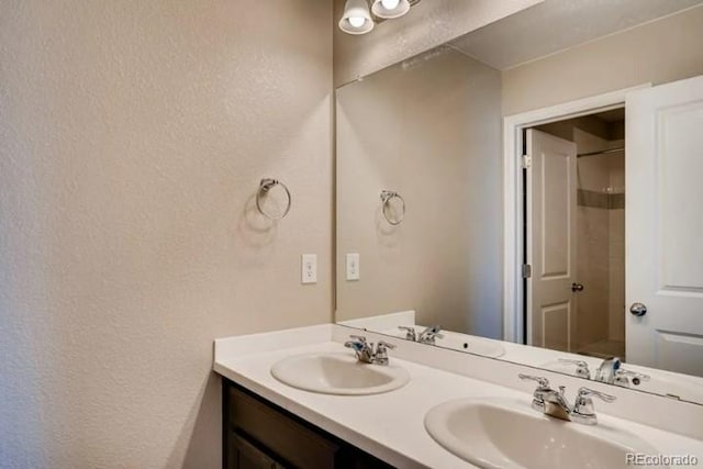 full bath with a textured wall, double vanity, and a sink