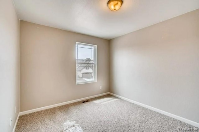 carpeted empty room featuring baseboards