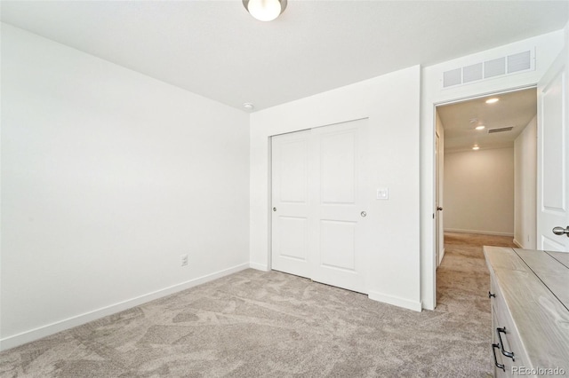 unfurnished bedroom featuring light colored carpet and a closet