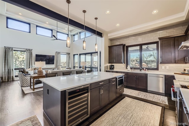 kitchen featuring wine cooler, stainless steel appliances, pendant lighting, a kitchen island, and tasteful backsplash