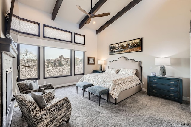 bedroom with carpet, beamed ceiling, a tiled fireplace, ceiling fan, and a high ceiling