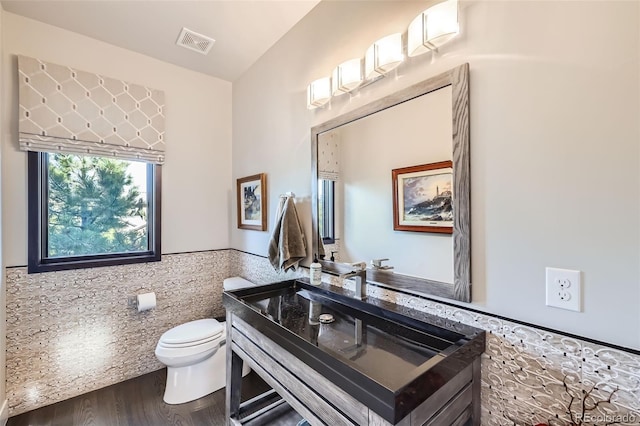 bathroom featuring toilet, hardwood / wood-style flooring, vaulted ceiling, tile walls, and vanity