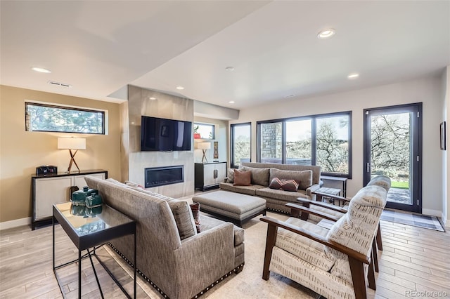 living room featuring a tile fireplace and a healthy amount of sunlight