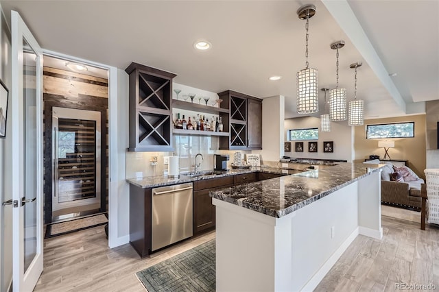 kitchen featuring pendant lighting, light wood-type flooring, dishwasher, and dark stone counters