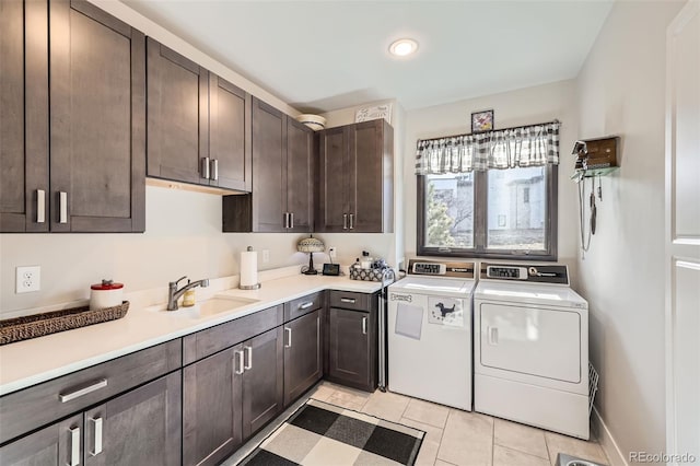 washroom with sink, cabinets, washing machine and dryer, and light tile patterned floors