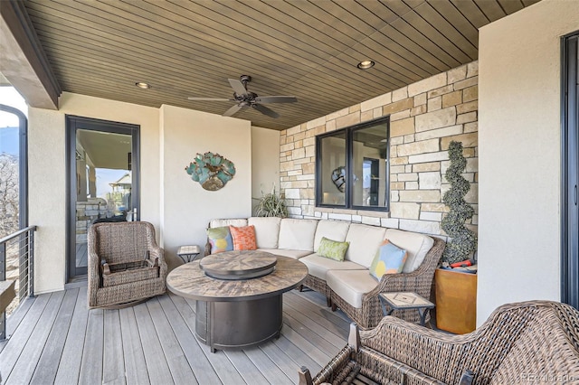 wooden deck featuring ceiling fan and an outdoor living space with a fire pit