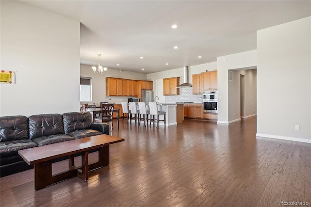 living room featuring an inviting chandelier, dark hardwood / wood-style floors, and sink