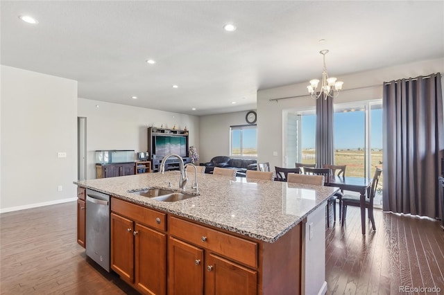 kitchen with a chandelier, dark hardwood / wood-style floors, sink, hanging light fixtures, and a center island with sink