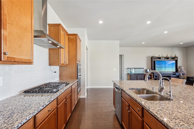 kitchen with light stone counters, dark hardwood / wood-style floors, sink, wall chimney exhaust hood, and stainless steel appliances