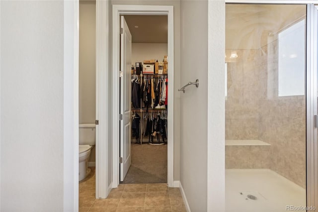 bathroom with tile patterned flooring, toilet, and tiled shower