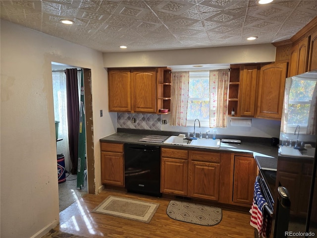 kitchen featuring sink, black dishwasher, light hardwood / wood-style floors, fridge, and range